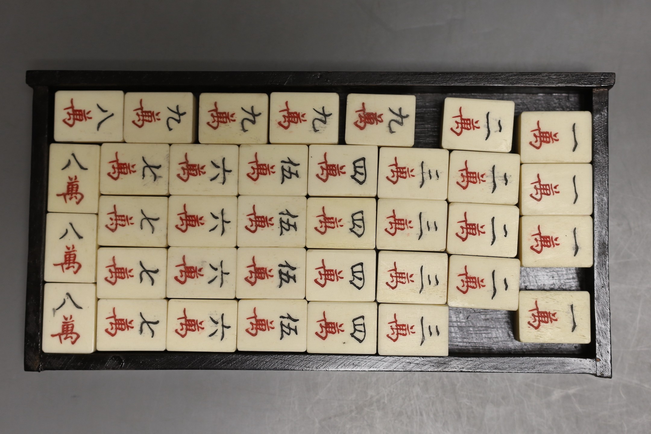 A Chinese boxed mahjong set, bone and bamboo gaming pieces, 24.5 cms wide x 16cms high.